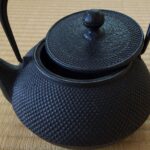 Schwarze japanische Gusseisen-Teekanne mit Hagelmuster auf einer Tatami-Matte