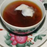 Tasse Ostfriesentee mit Sahnewolke auf einer Untertasse mit Rosendekor