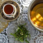 Tasse Darjeeling-Tee neben Schalen mit verschiedenen losen Teesorten und frischen Teeblättern