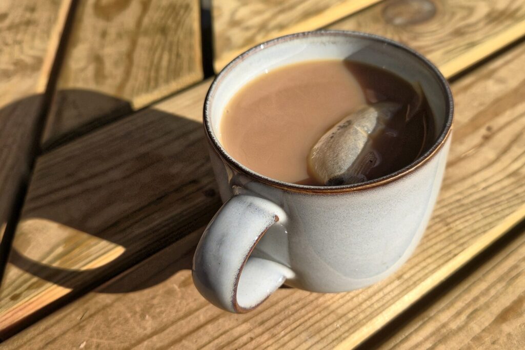 Keramiktasse mit Tee auf einem sonnenbeschienenen Holztisch